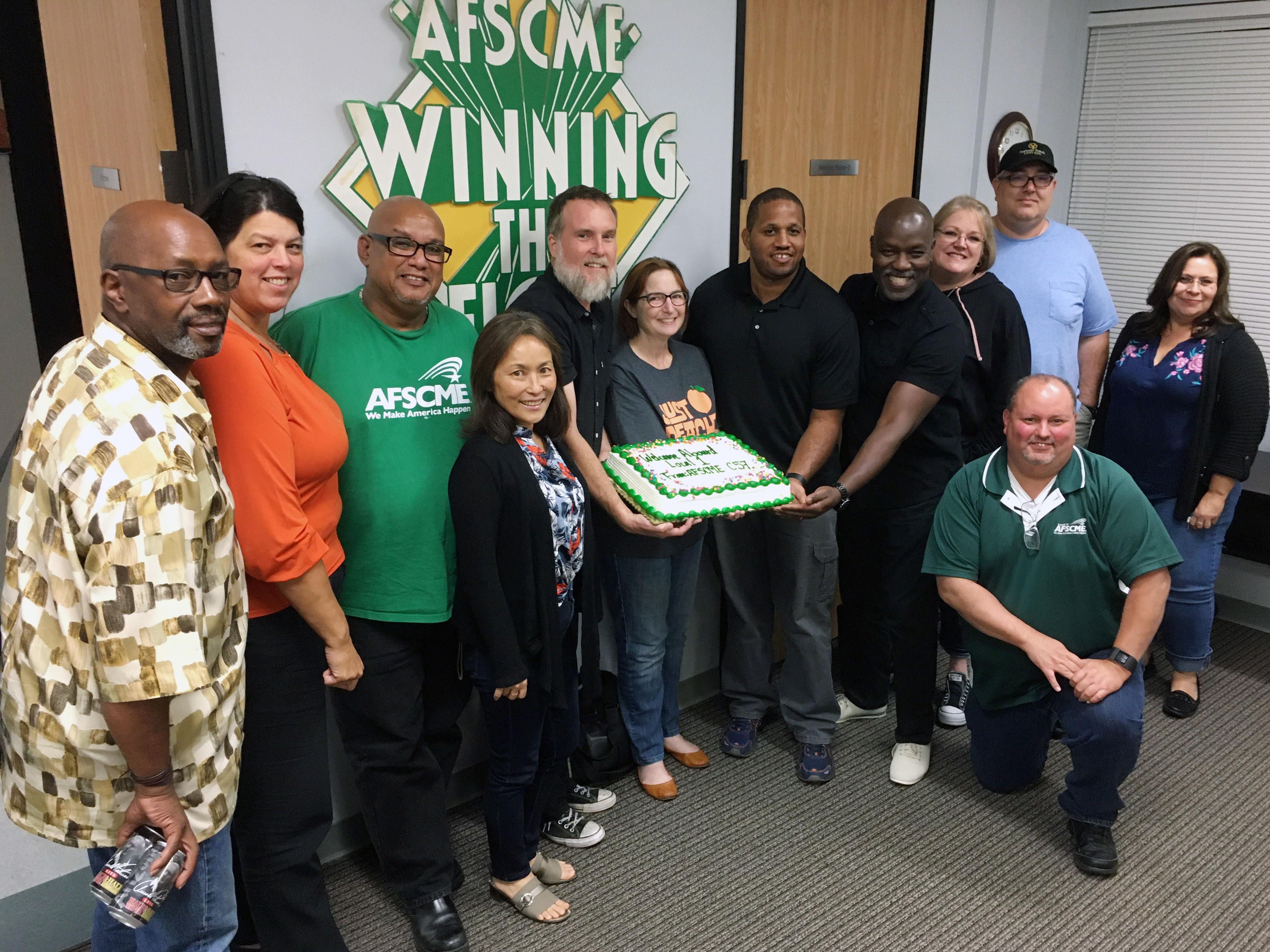 Local 1 leaders and Council 57 board members celebrate merger with a cake
